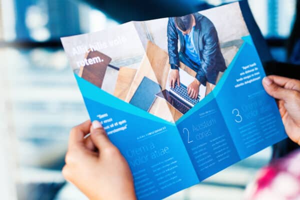 person holding a mockup of a trifold brochure in their hands