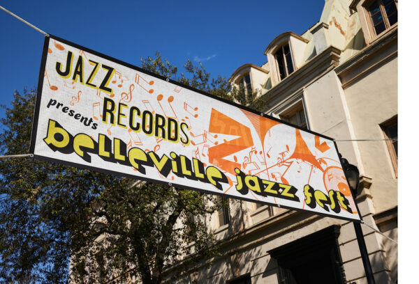 example of vinyl banner that says "Jazz Records presents belleville jazz fest" hanging up with houses and trees in the background