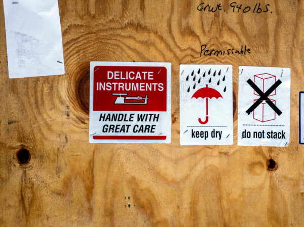 labels shown on plywood that say "handle with great care", "keep dry", and "do not stack"
