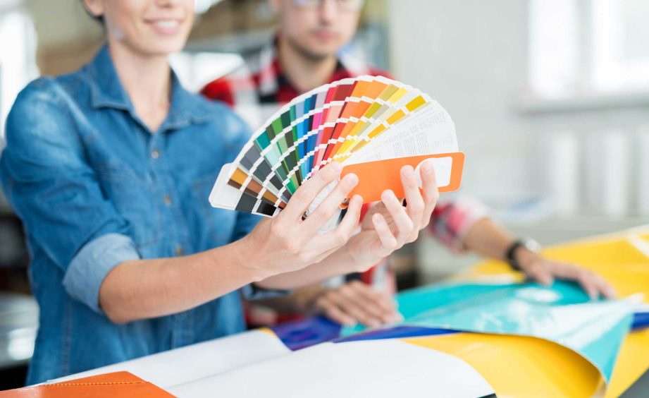 image of a woman holding a fanned out color book while review print job for color accuracy